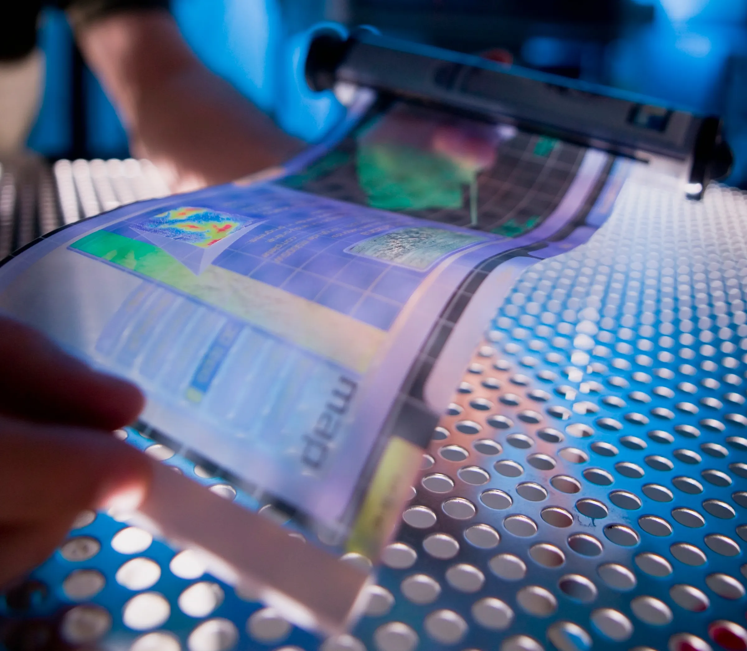 A thin, flexible electronic display being bent by hand.